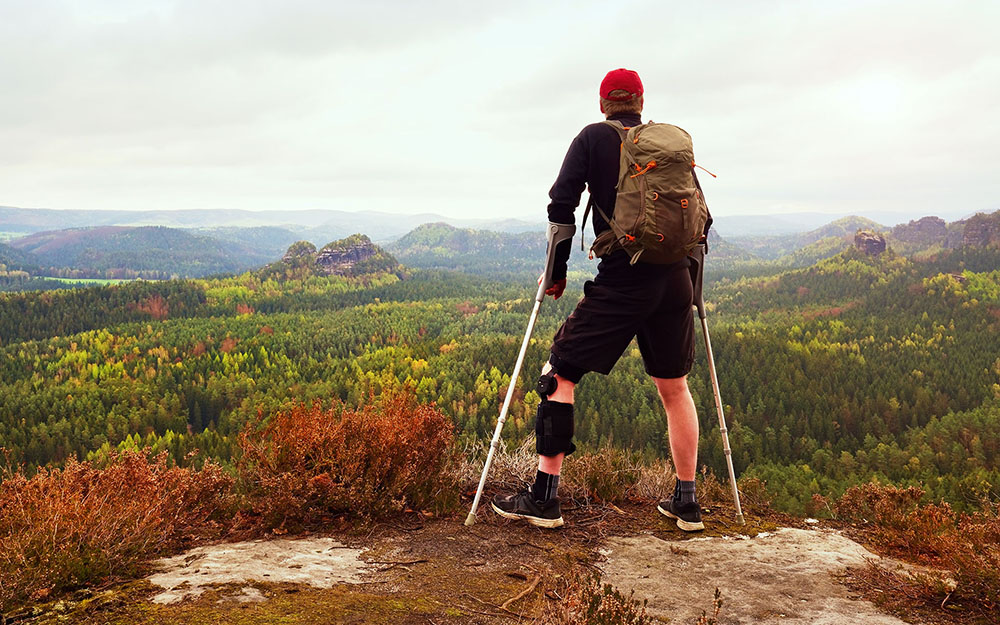 Hiker wearing supportive leg brace and gainst the cruthes.