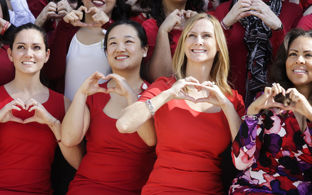 A group of people making heart signs with their hands for heart month awareness