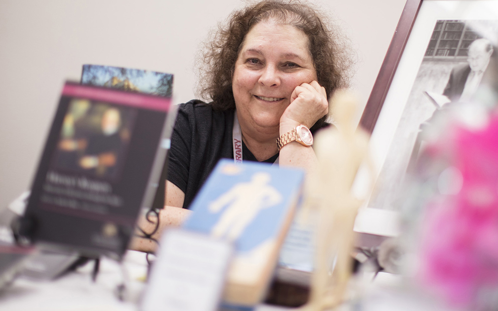 Janet Wulf sits behind a table of materials for an upcoming library display.
