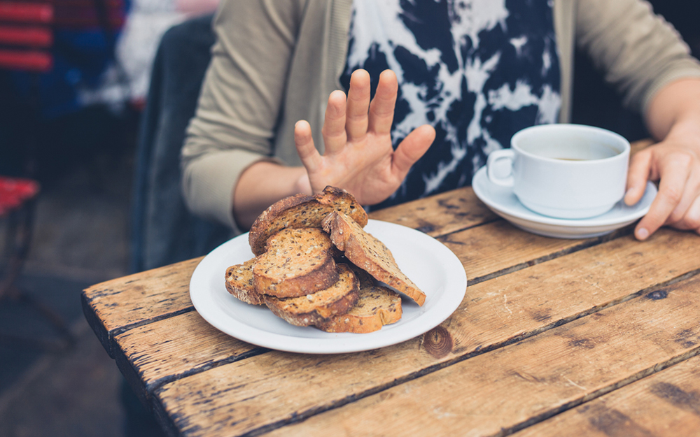 A woman refusing bread at a restaurant to avoid triggering her celiac disease.