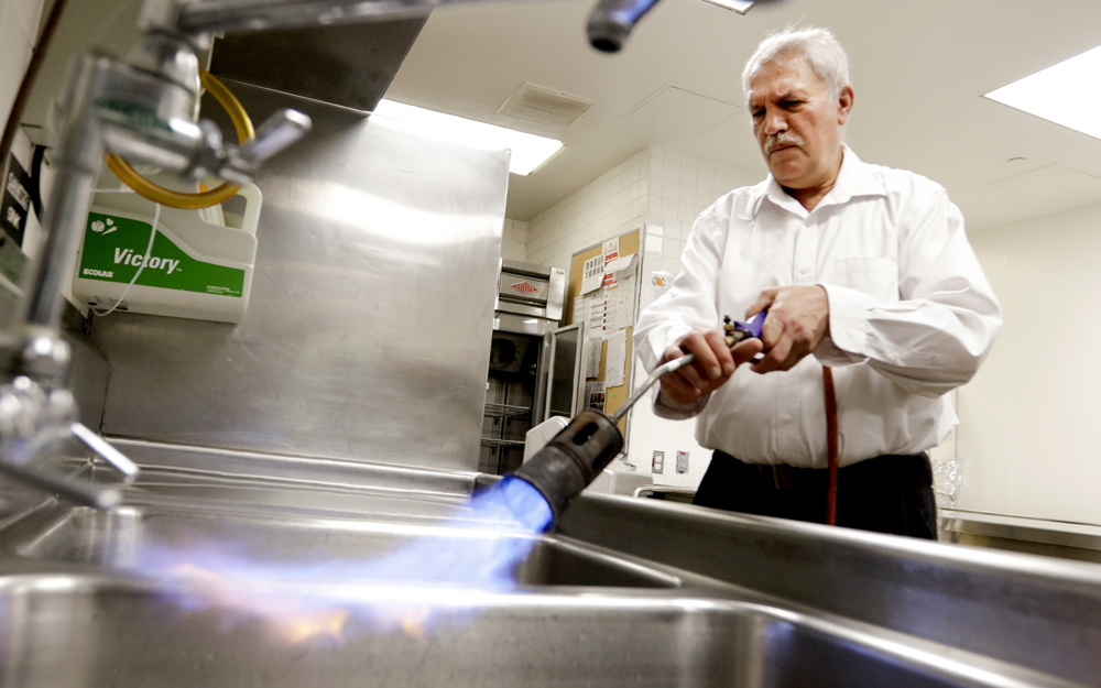 Benjamin Saghizadeh a Mashgiach from the Rabbinical Council of California uses a propane blowtorch to cleanse the metal kitchen sink in preparation for Passover. In Preparation for Passover, the kosher kitchen cleans all appliances and metal surfaces with fire or hot water.