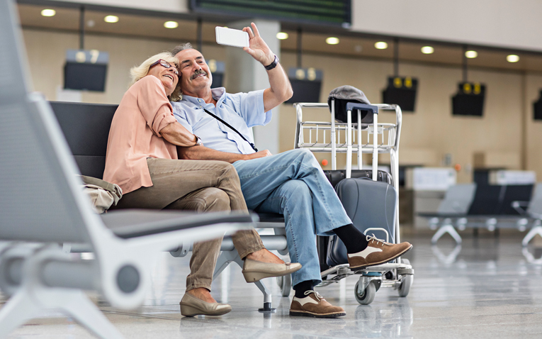 Elderly couple taking a selfie at the airport.