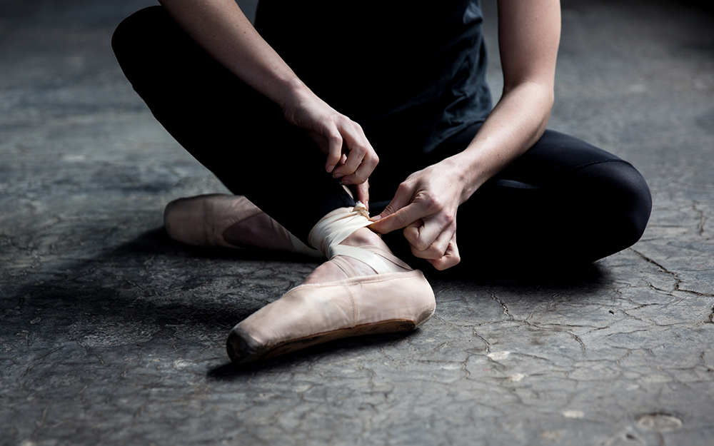 Dancer wearing ballet shoe in studio.