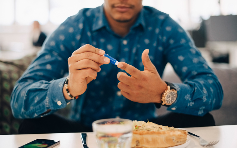 A young adult with type 1 diabetes tests his glucose level before eating.