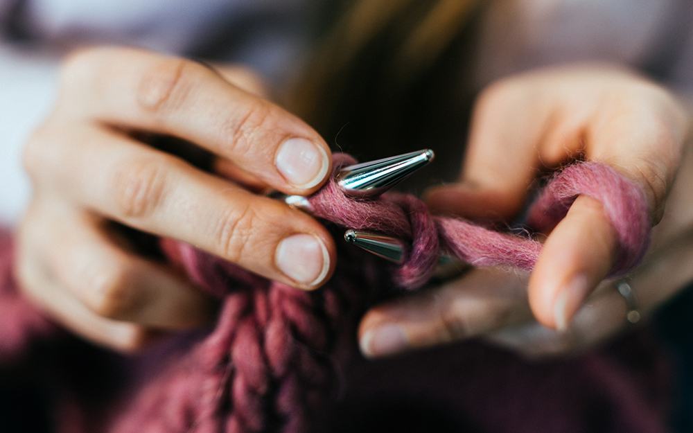 A close-up photo of a woman with rheumatoid arthritis hands while knitting.