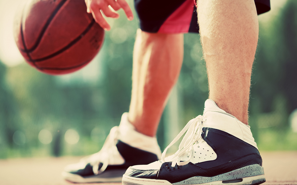 An older white man playing basketball trying to avoid a torn achilles tendon.