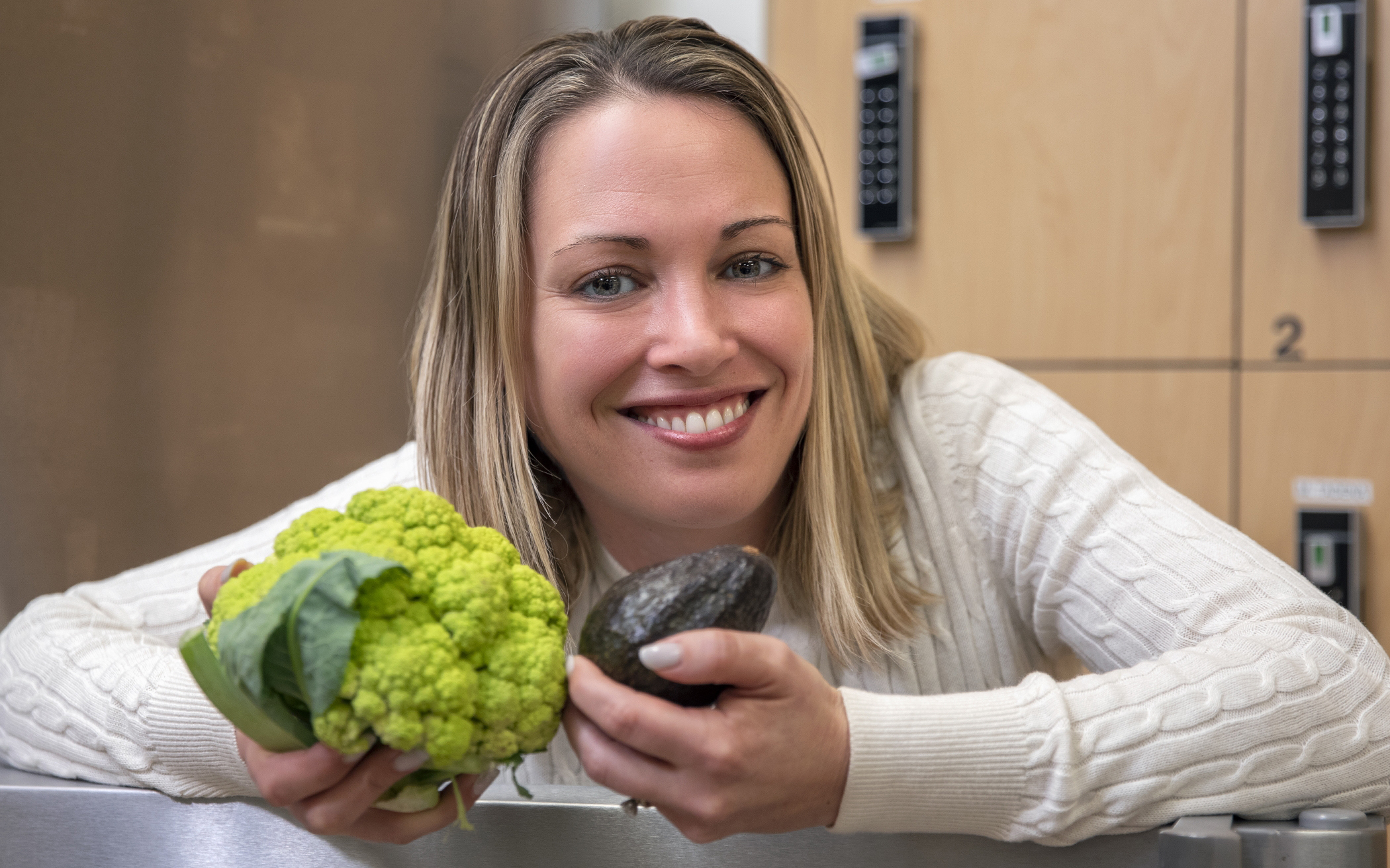 Woman holding a cauliflower and avocado.
