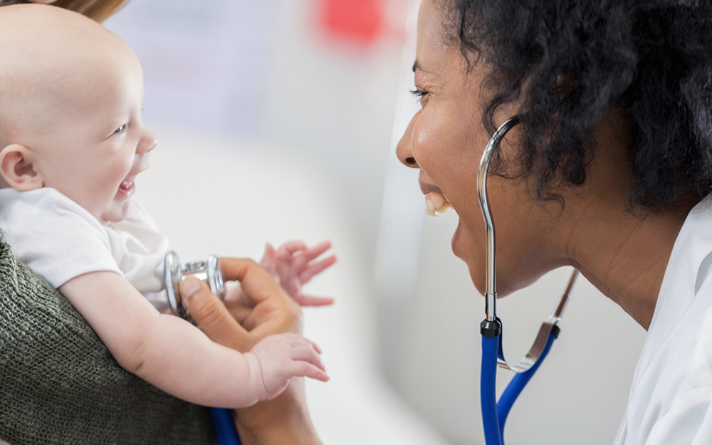 Woman doctor listening to a newborn baby's heartbeat.