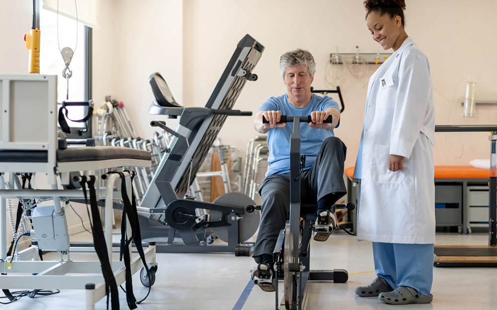 Older man doing therapy on exercise bike.