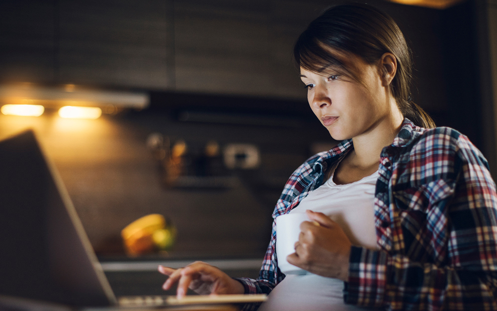 A young pregnant woman reading the internet worried about preeclampsia.