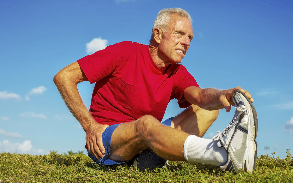 An older man stretching to avoid a hamstring injury.