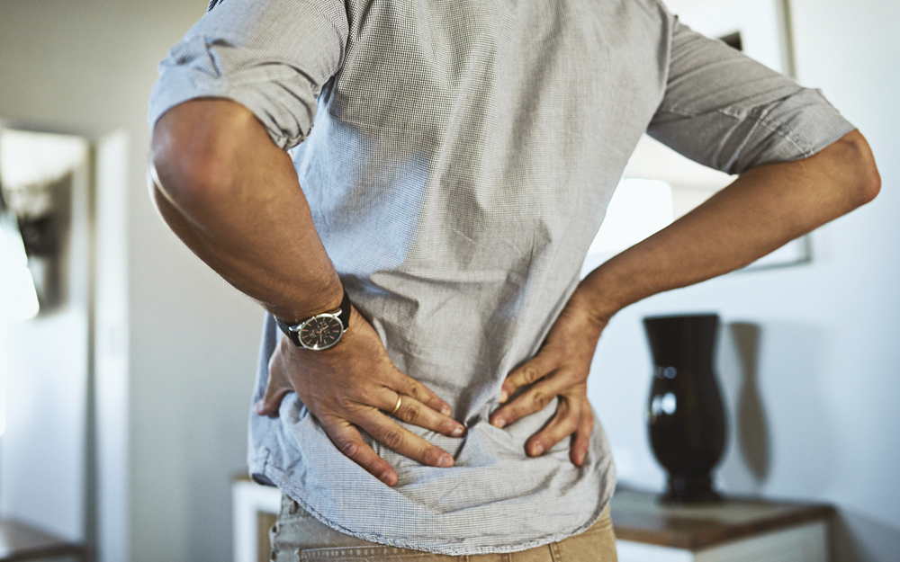 A man grasping his lower back in pain.