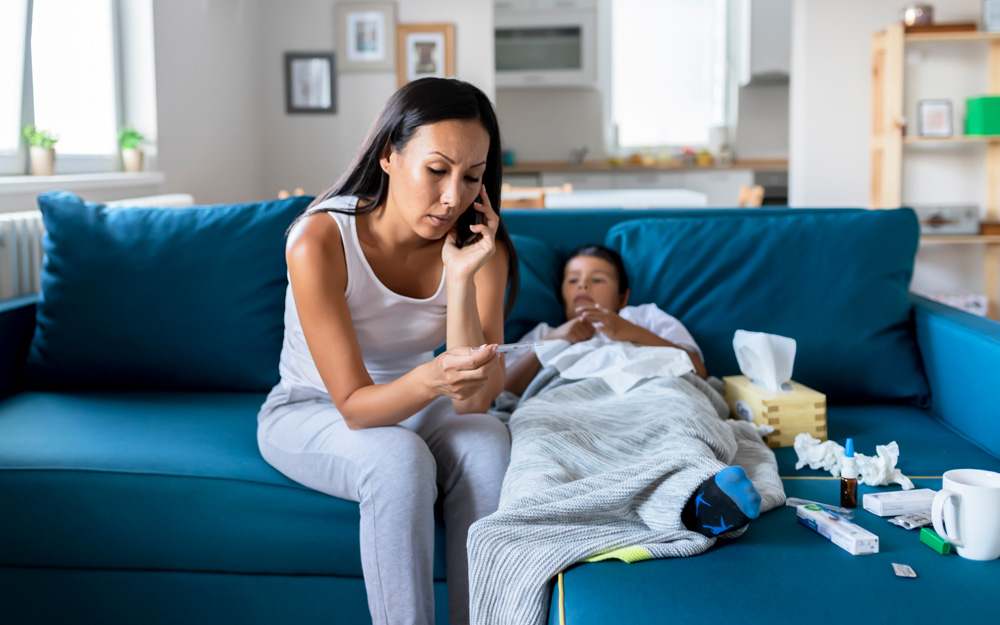 Mother on the phone next to her sick child.