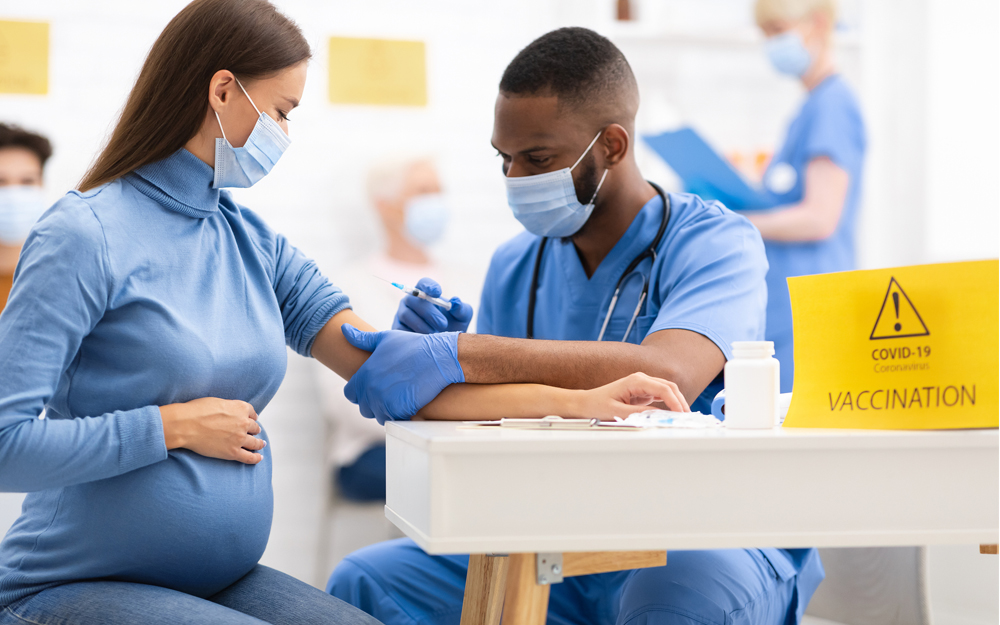 A pregnant woman getting a COVID-19 vaccination from a healthcare worker.