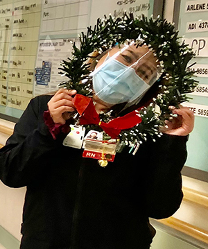A nurse posing by the nursing station with a garland
