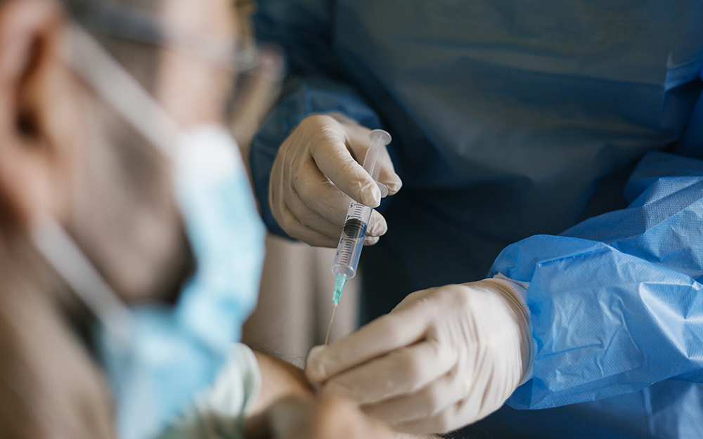 Man in a mask getting a vaccine booster shot.