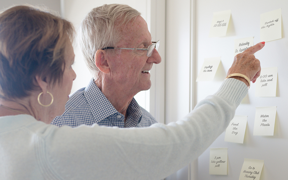 Elderly couple pointing and looking at sticky notes reminders