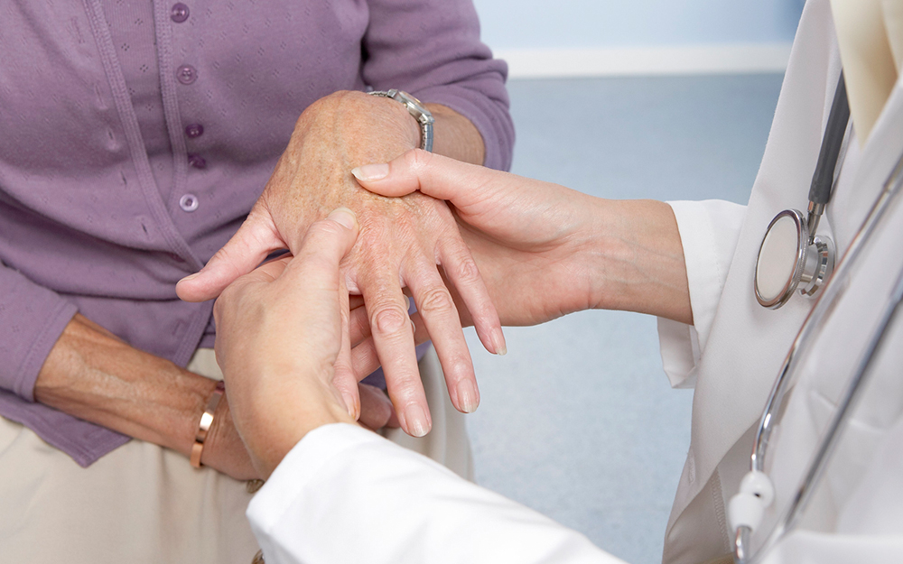 Woman getting her hand checked by doctor.