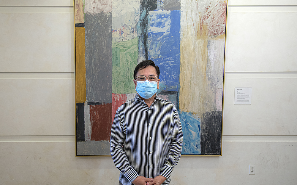 Lorenzo D. San Pedro, MSN, RN, Education Program Coordinator of Cedars-Sinai Samuel Oschin Cancer Center standing in front of Ernst Briggs, "June".