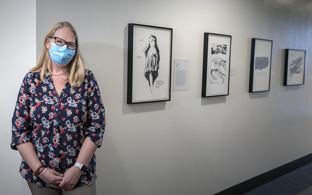 Virginia Bartlett, PhD, Assistant Director of Center for Healthcare Ethics at Cedars-Sinai standing in front of  Raymond Pettibon prints in the hall behind the chapel.