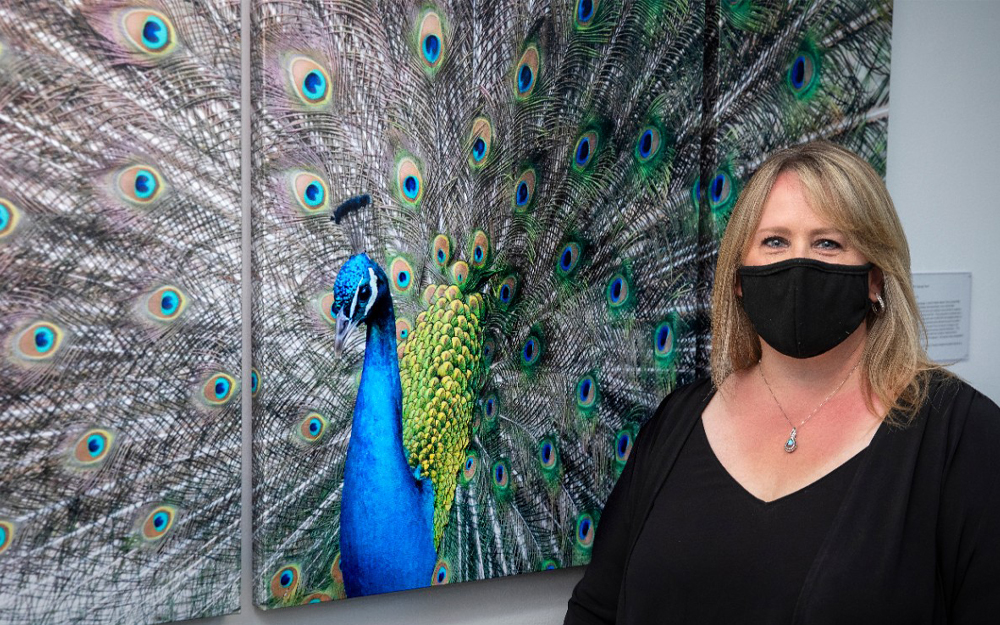 Cedars-Sinai employee posing for a picture with a photograph of a peacock