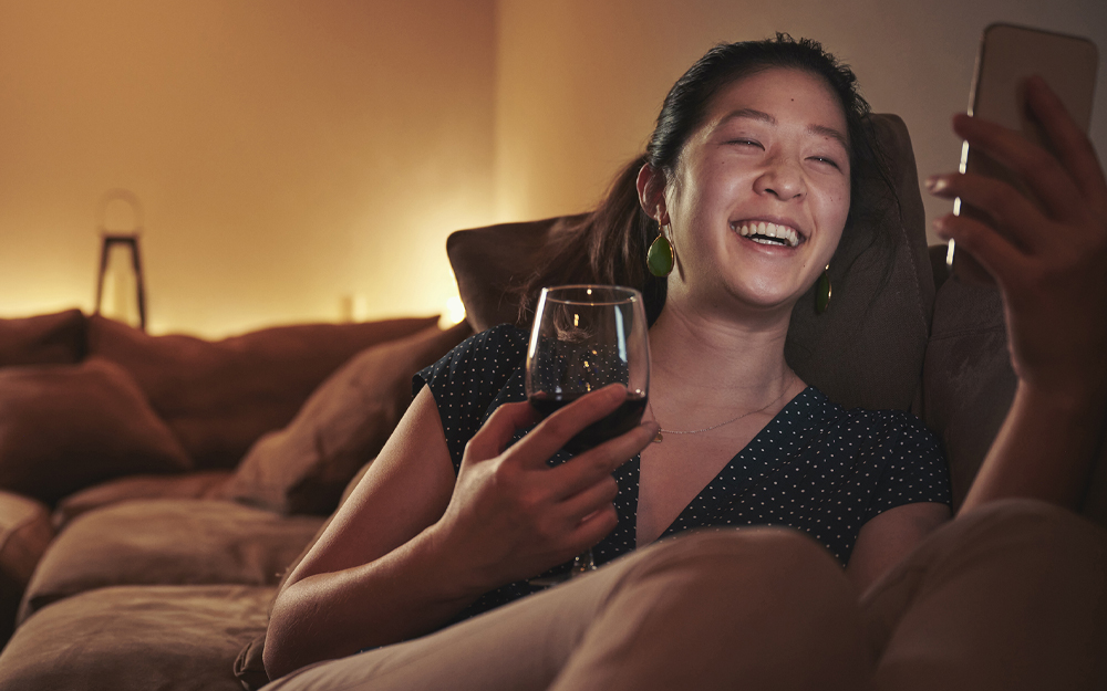 A woman drinking while texting on her phone