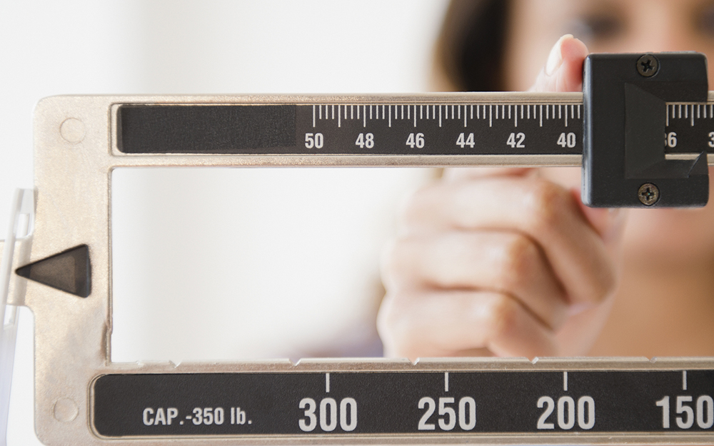 Woman weighing herself on scale. 