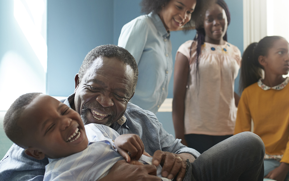 African American man playing with a boy on sofa at home