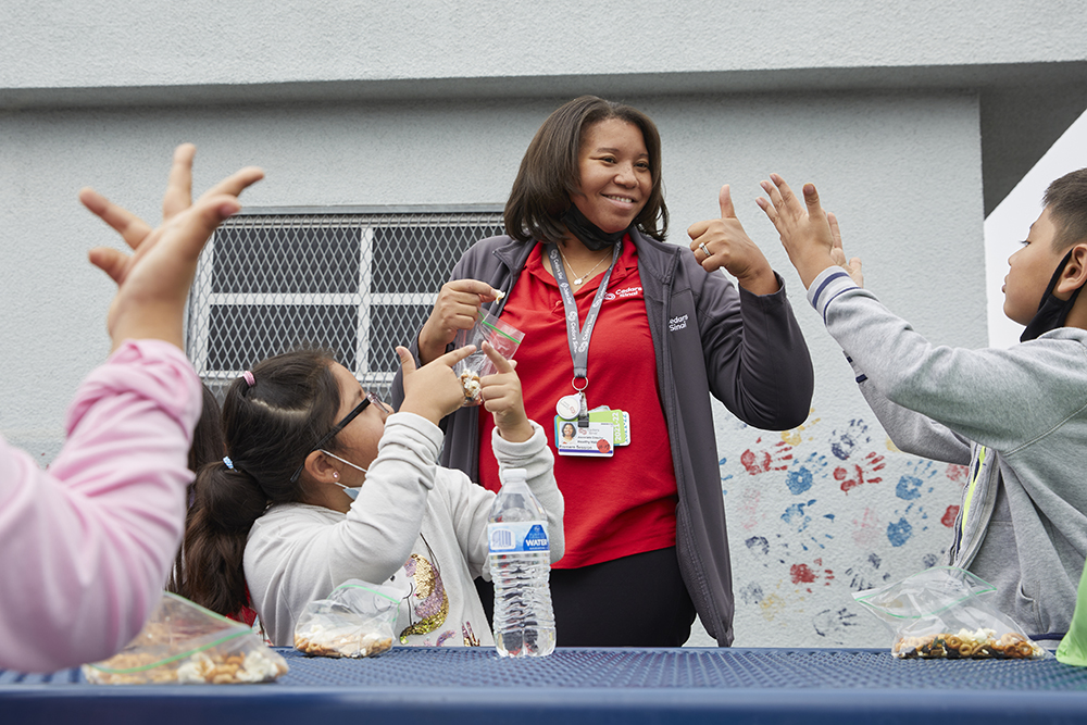 Premere Sessions outside with a few second graders eating snacks.