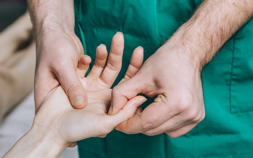 A doctor checks a female patient for skier's thumb, ulnar collateral ligament, injury.