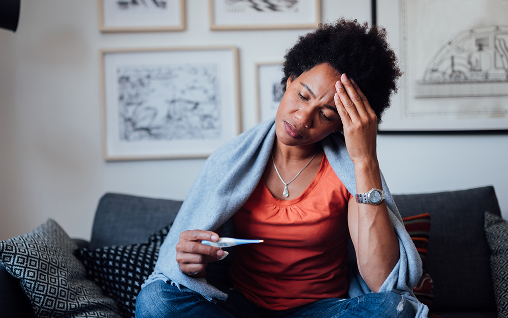 Worried African American woman sitting at home while being sick