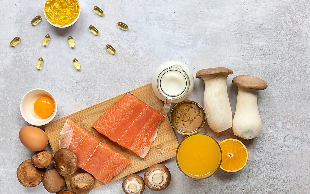 Flat lay composition with products rich in vitamin D. Canned tuna, mushrooms, salmon, eggs, milk, and orange juice.