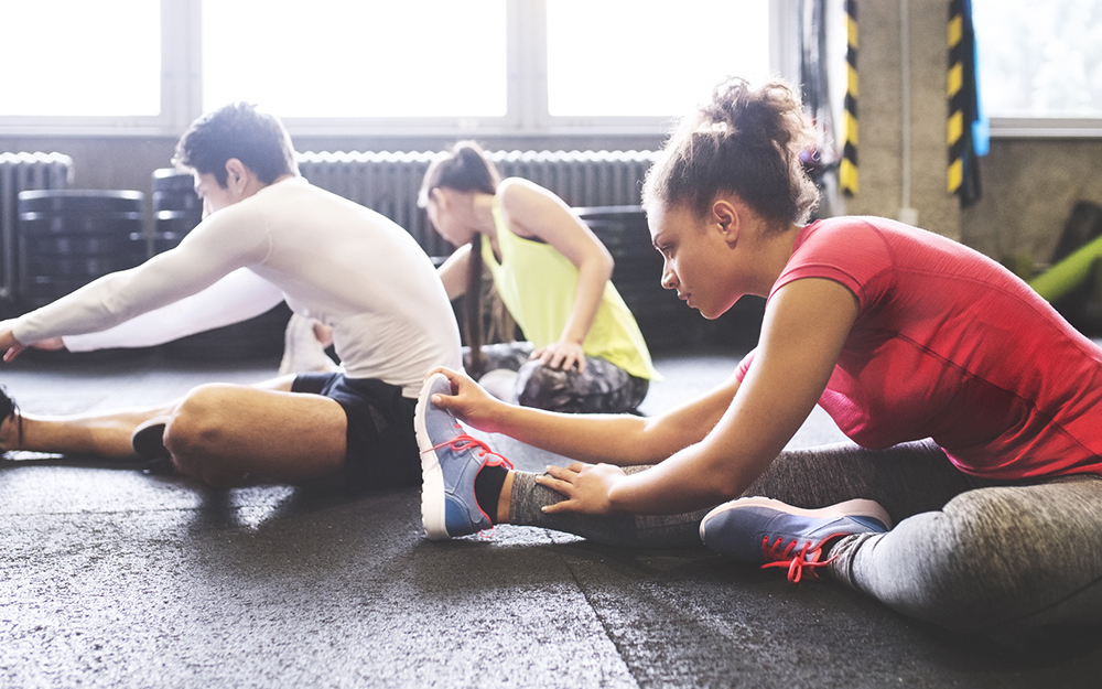 Three young people stretching in gym