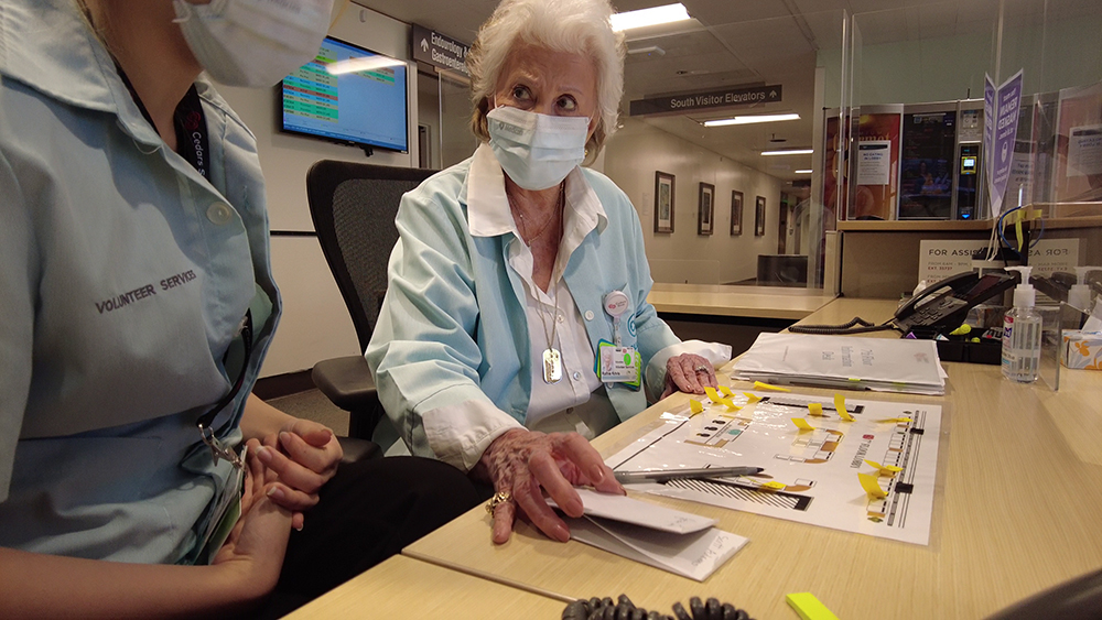 Ruthie Krivis at desk with nurse.