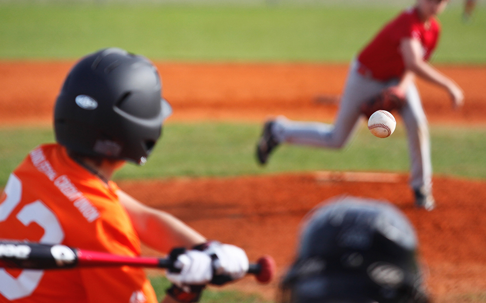 Little League baseball pitcher throwing ball toward batter.