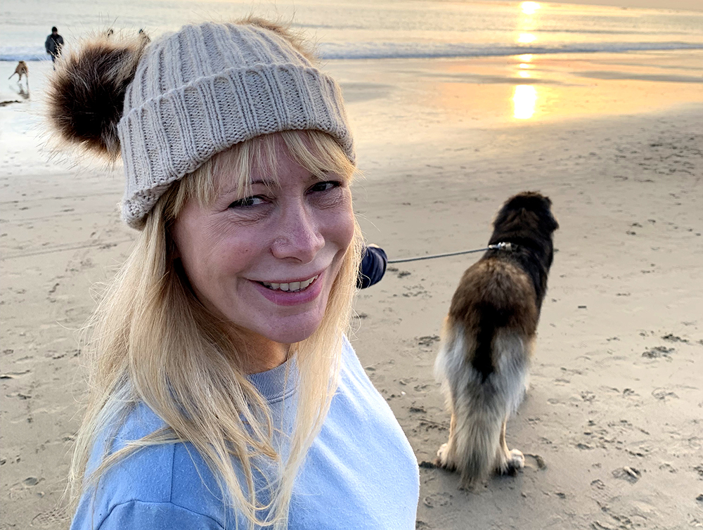 Cedars-Sinai Thunderclap Headache patient Julie Hunter walking her dog at the beach on sunset.