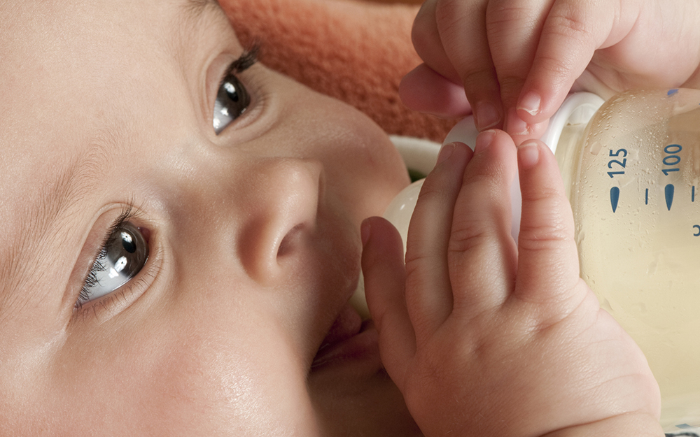 Newborn baby drinking milk from a bottle.