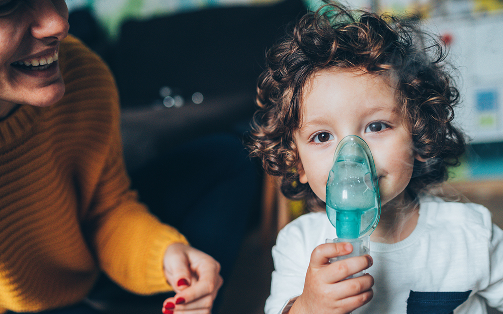 Mother helps her little boy to makes inhalation at home