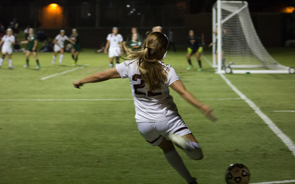 Women playing soccer on field.