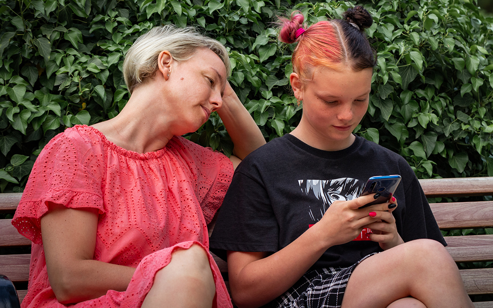 Teen girl holding mobile phone and looking at the screen.