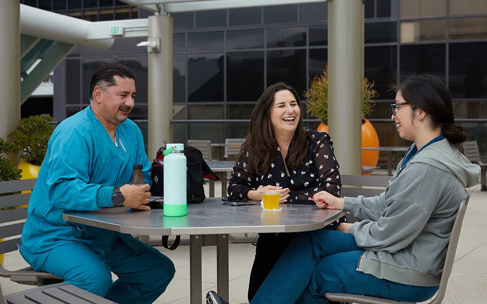 Jorge Arredondo, Stacey Arredondo and Fabiola Romero sitting at a table outside.