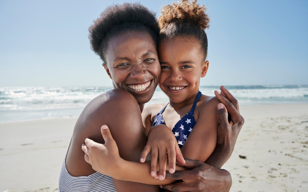 An African American mother and child in the sun at the beach.
