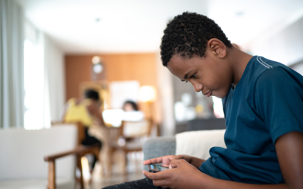 A young teen hunched over playing a handheld game.