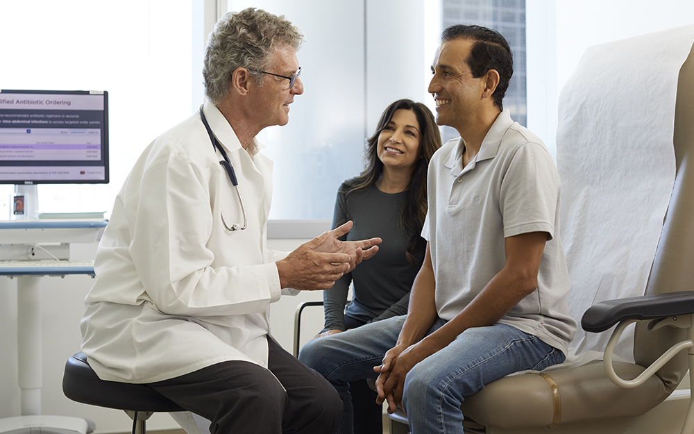 Doctor speaking with man and woman in office.