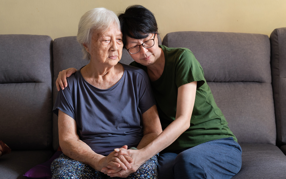 An asian woman sitting with her older mother.