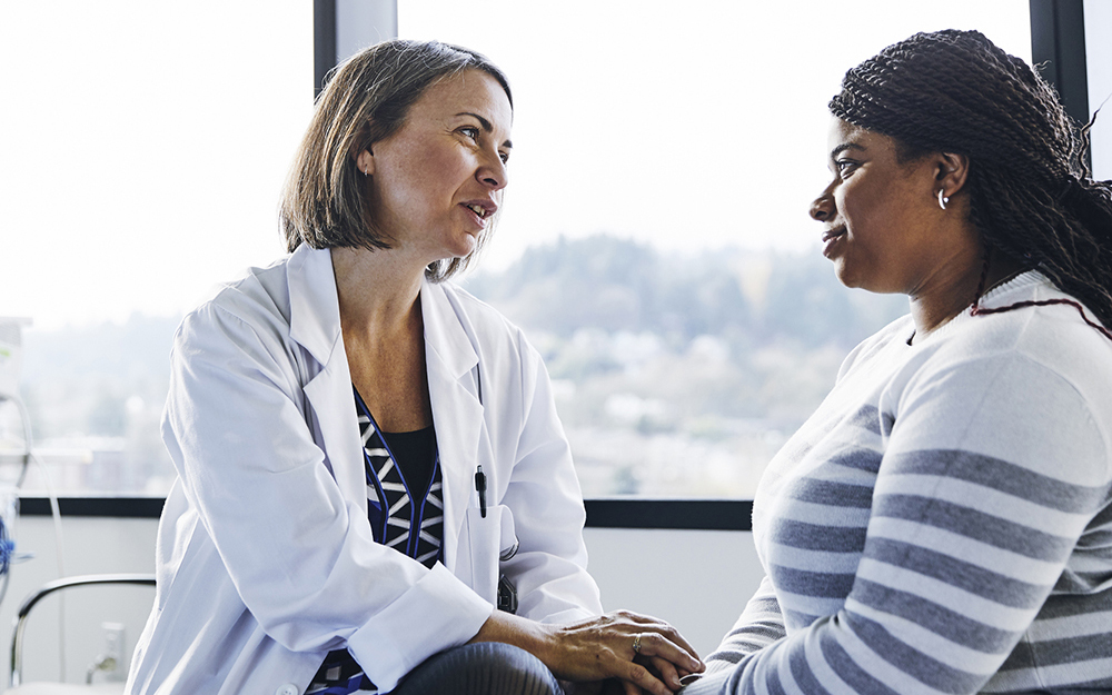 Smiling doctor talking to young woman in hospital 