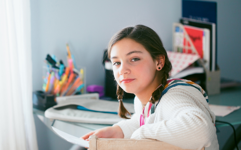 Girl working on homework at desk in her bedroom