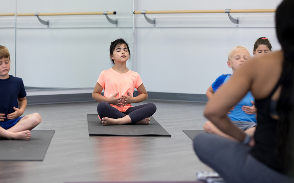 Kids doing breathing exercises with a teacher