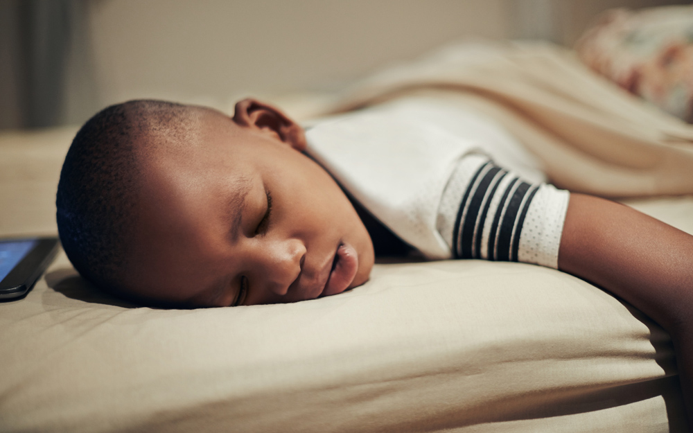 A young boy snoring while he sleeps with his mouth open.