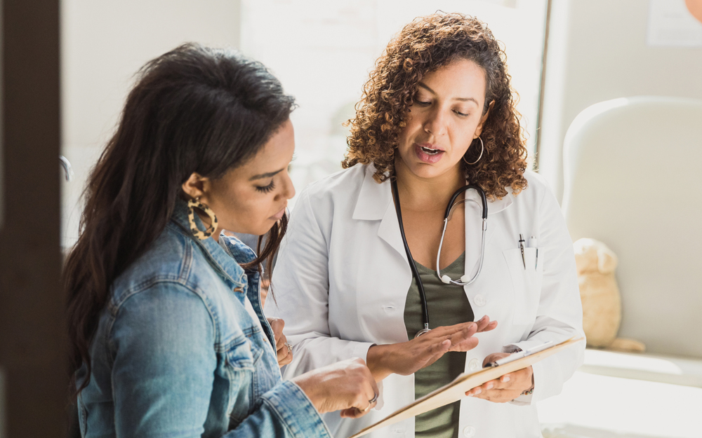 A young Latina woman specking with her physician.